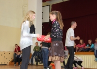 Laura Vīksniņa pasniedz jaunos apavus meitenei Kazdangas Māteru Jura pamatskolā